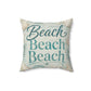 A square decorative throw pillow with a beach theme, featuring the words 'Beach Beach Beach' in teal script and block lettering on a light blue and white textured background with seashell and palm leaf illustrations.