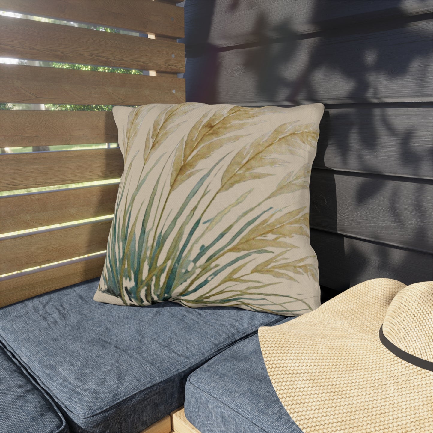 Decorative pillow with leaf pattern on a blue cushioned outdoor bench.