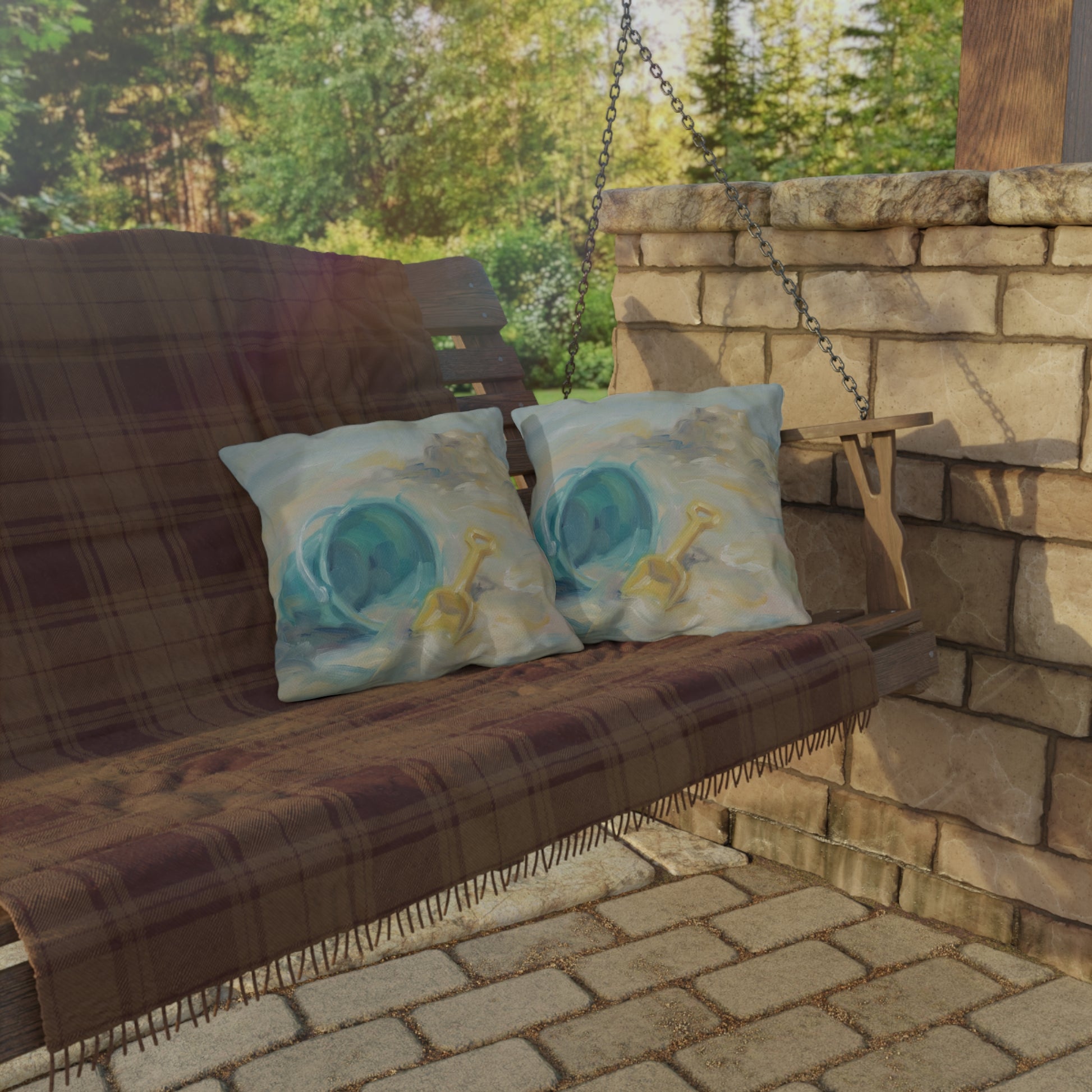 Wooden swing with plaid cover and decorative pillows on a stone patio