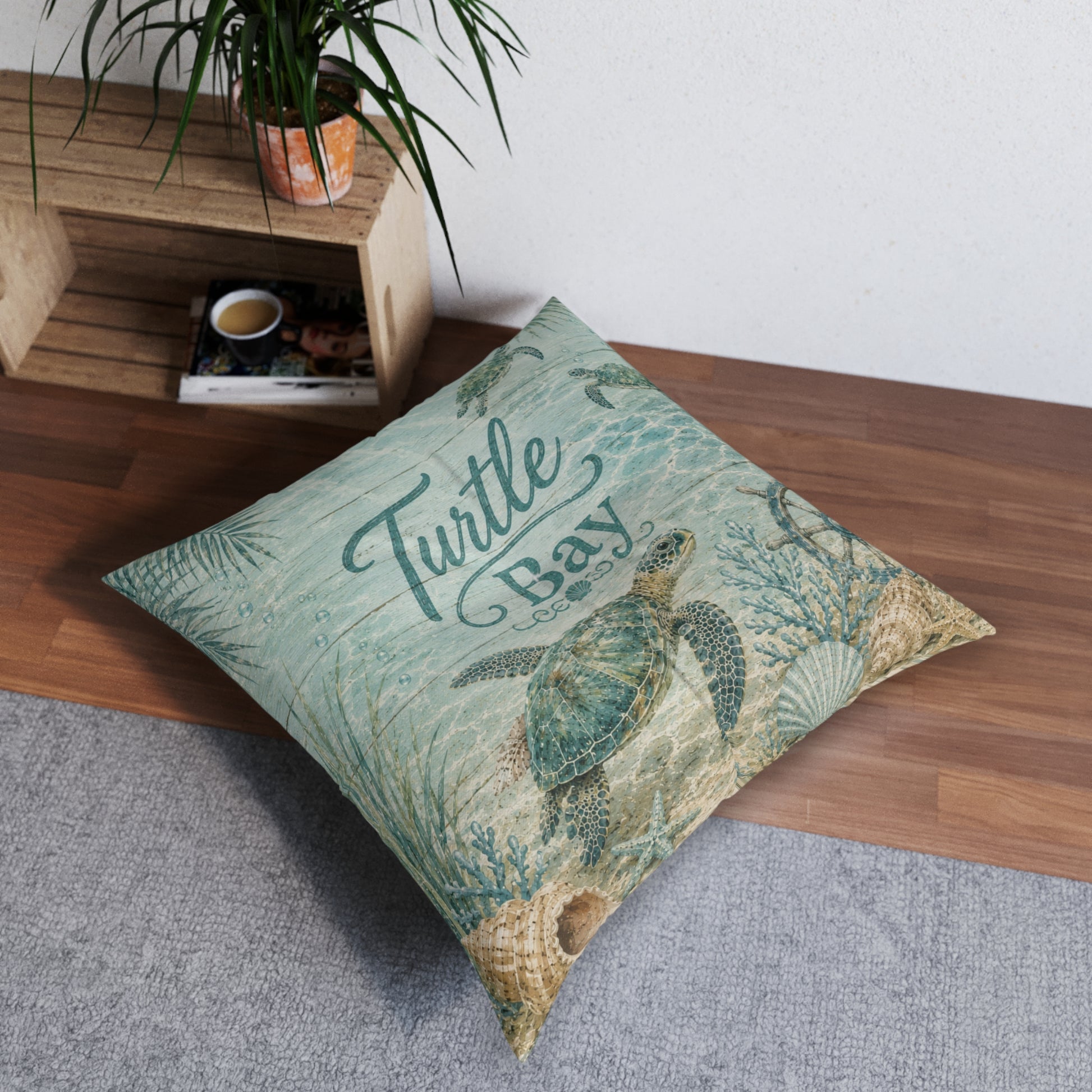Square turquoise tufted floor pillow with sea turtle artwork and “Turtle Bay” text