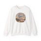 An off-white crewneck sweatshirt featuring a circular graphic on the chest with a beach scene and the text 'Autumn Beach Life'.