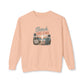A peach-colored crewneck sweatshirt featuring a retro-style graphic on the chest that reads 'Beach DREAMS' above a beach scene with palm trees, a sunset, and a boardwalk sign.