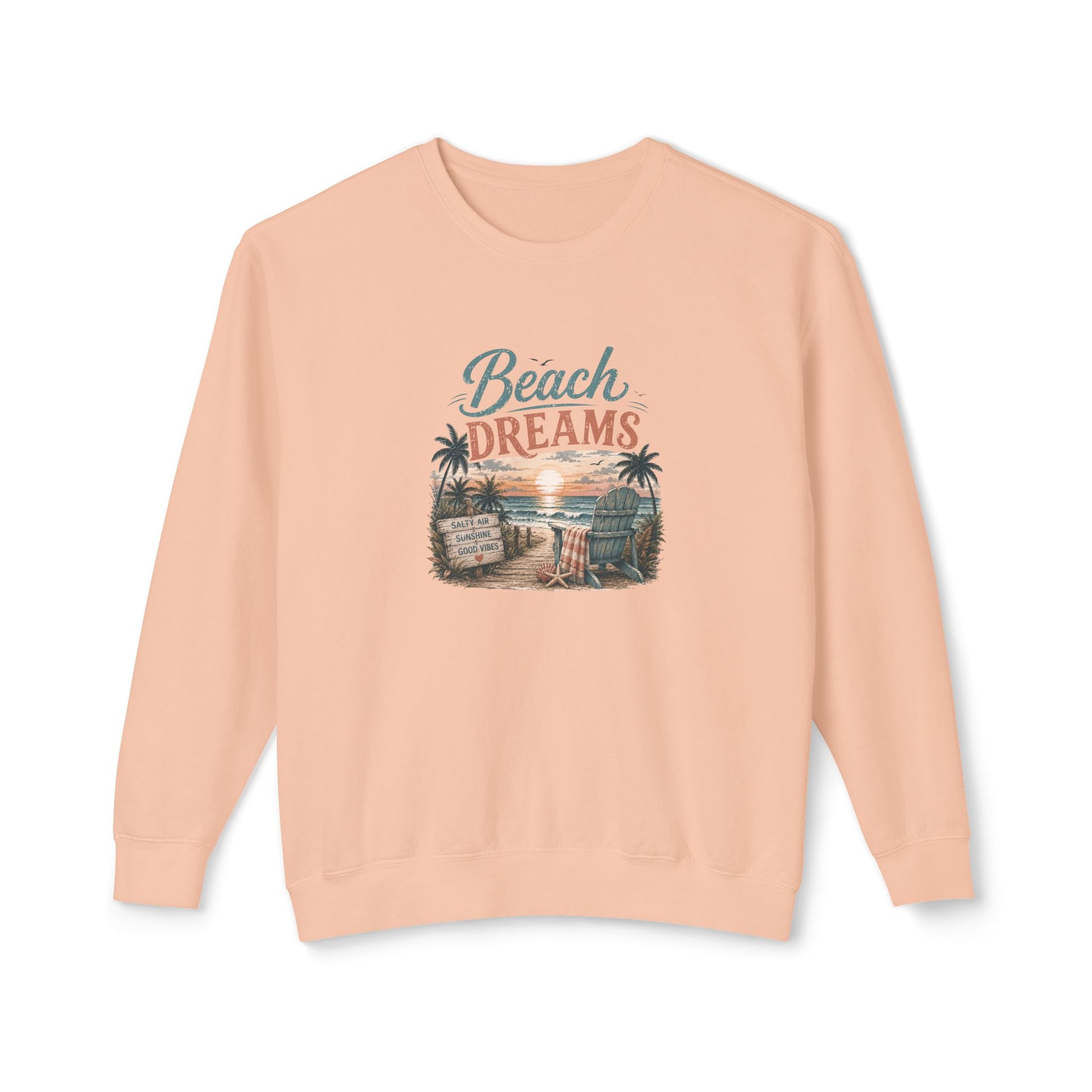 A peach-colored crewneck sweatshirt featuring a retro-style graphic on the chest that reads 'Beach DREAMS' above a beach scene with palm trees, a sunset, and a boardwalk sign.
