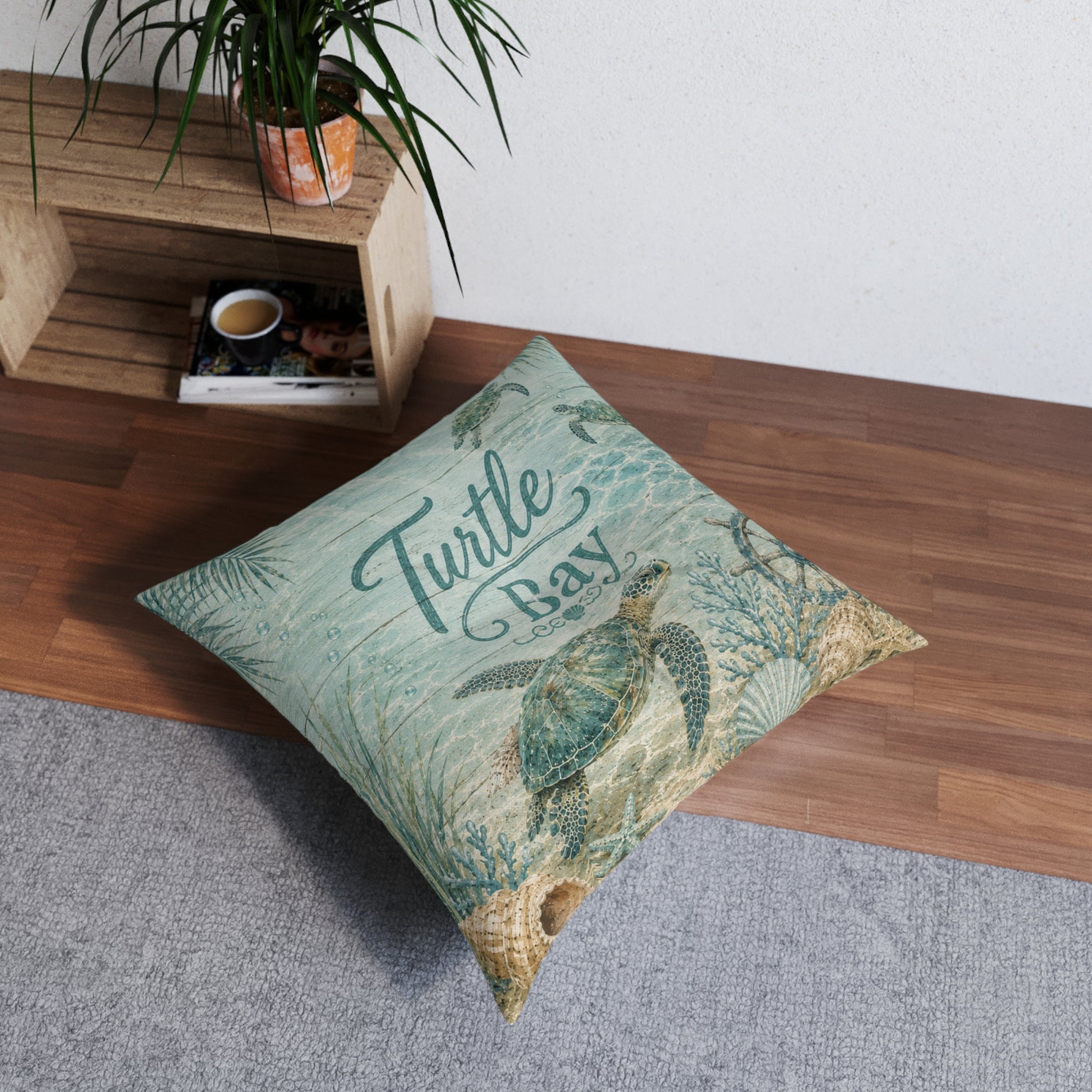 Square turquoise floor pillow with sea turtle print and “Turtle Bay” text, tufted look
