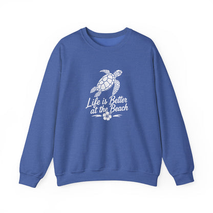 A blue crewneck sweatshirt featuring a white graphic of a sea turtle and the text 'Life is Better at the Beach' with a small flower design, displayed on a clean white background.