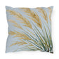 Decorative pillow with gold and green leaf pattern on a light blue background