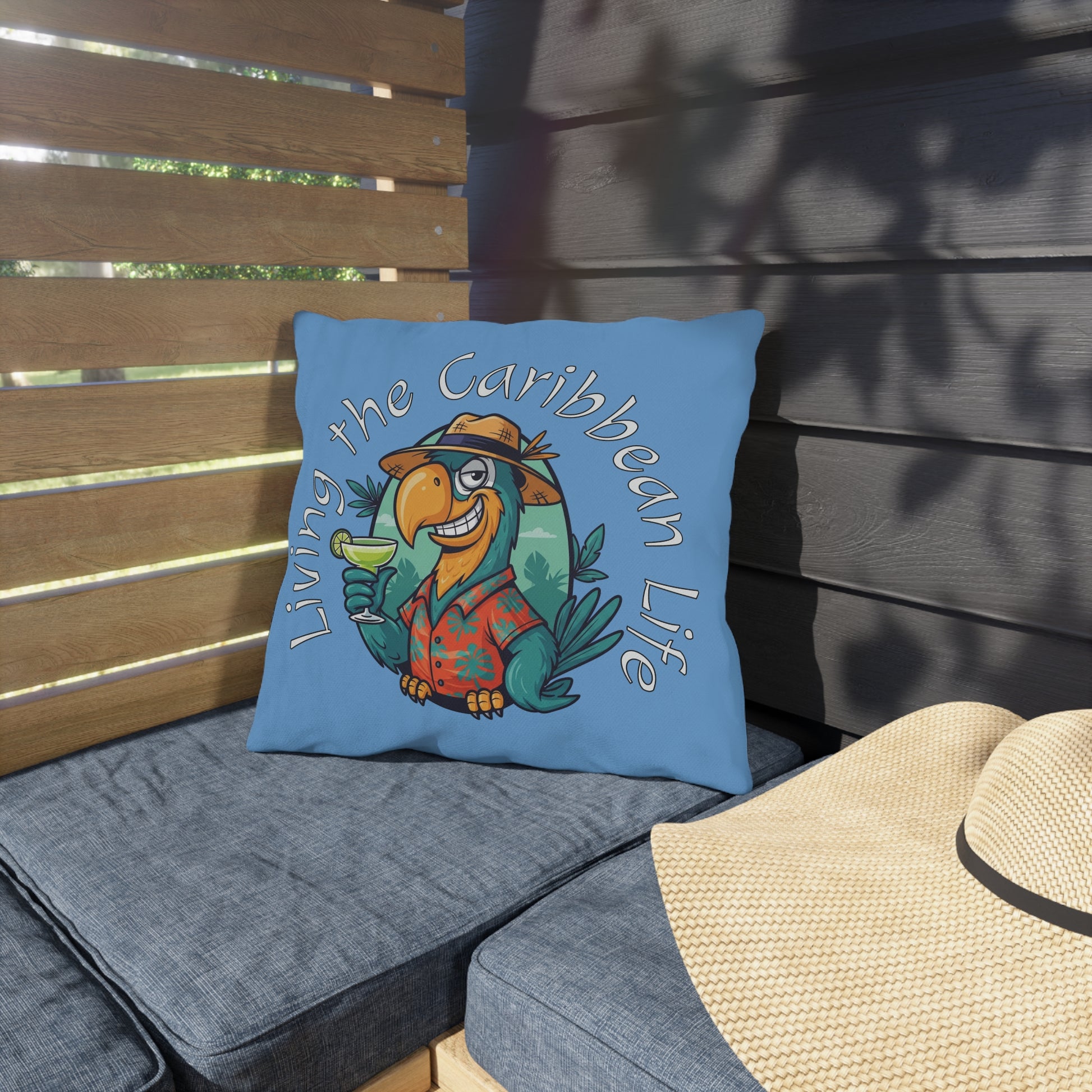Blue pillow with a tropical bird design and text 'Living the Caribbean Life' on a wooden bench.