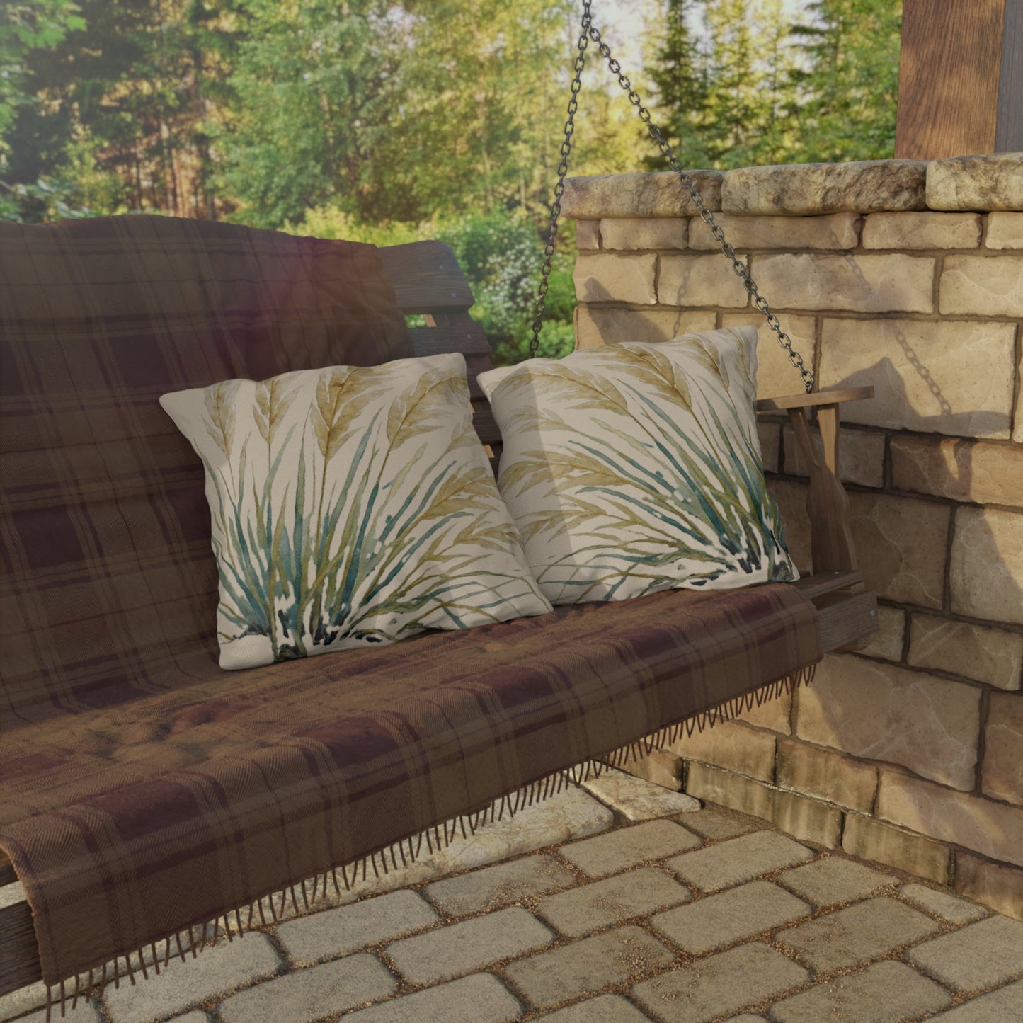Wooden swing with plaid cover and leaf-patterned cushions against a stone wall and greenery background