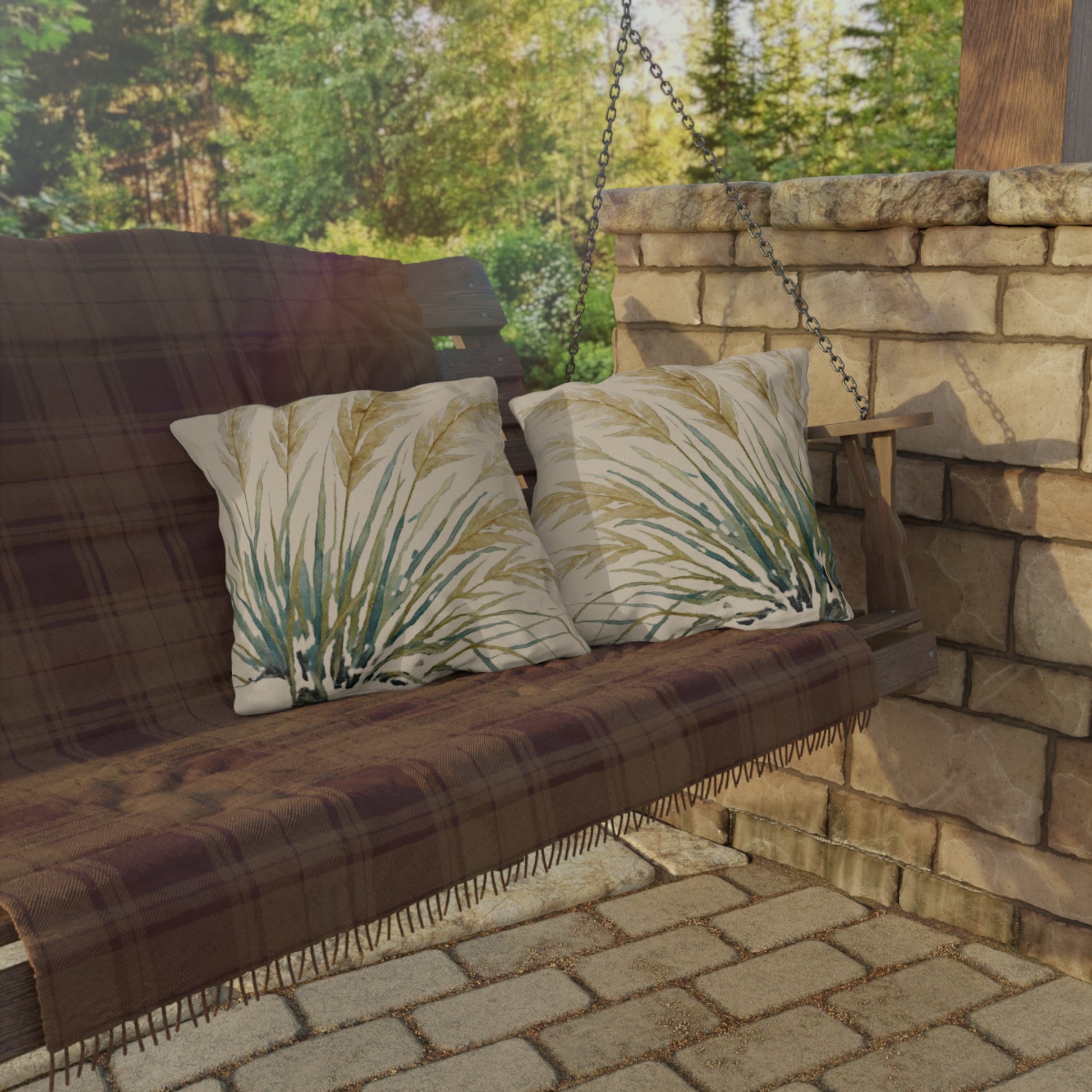 Wooden swing with plaid cover and leaf-patterned cushions against a stone wall and greenery background