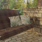 Wooden swing with plaid blanket and patterned pillows against a stone wall and greenery.