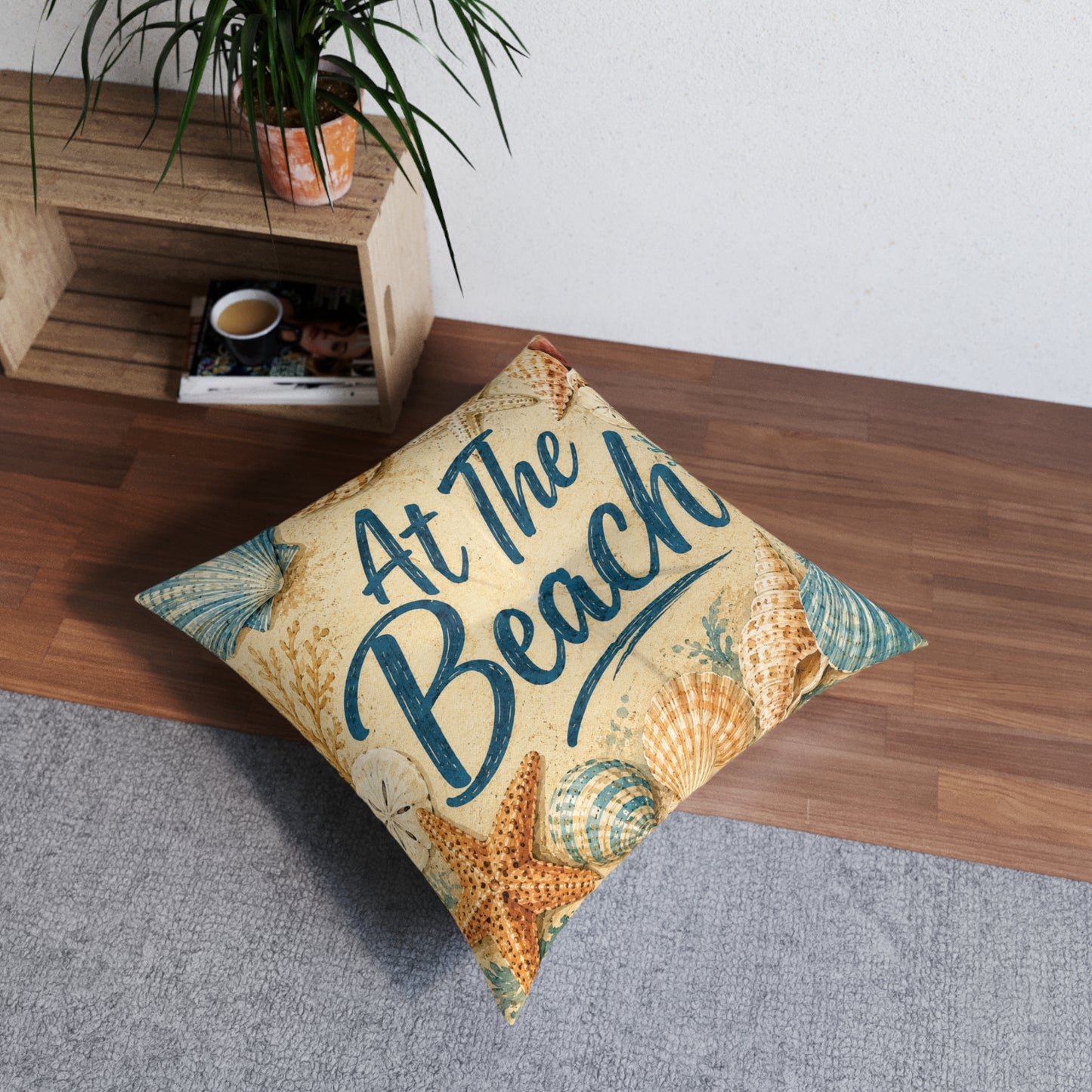 Square tufted floor pillow, beige with seashells and teal 'At The Beach' lettering