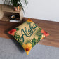 Square tufted floor pillow with Aloha text, tropical palm leaves, and hibiscus flowers on tan