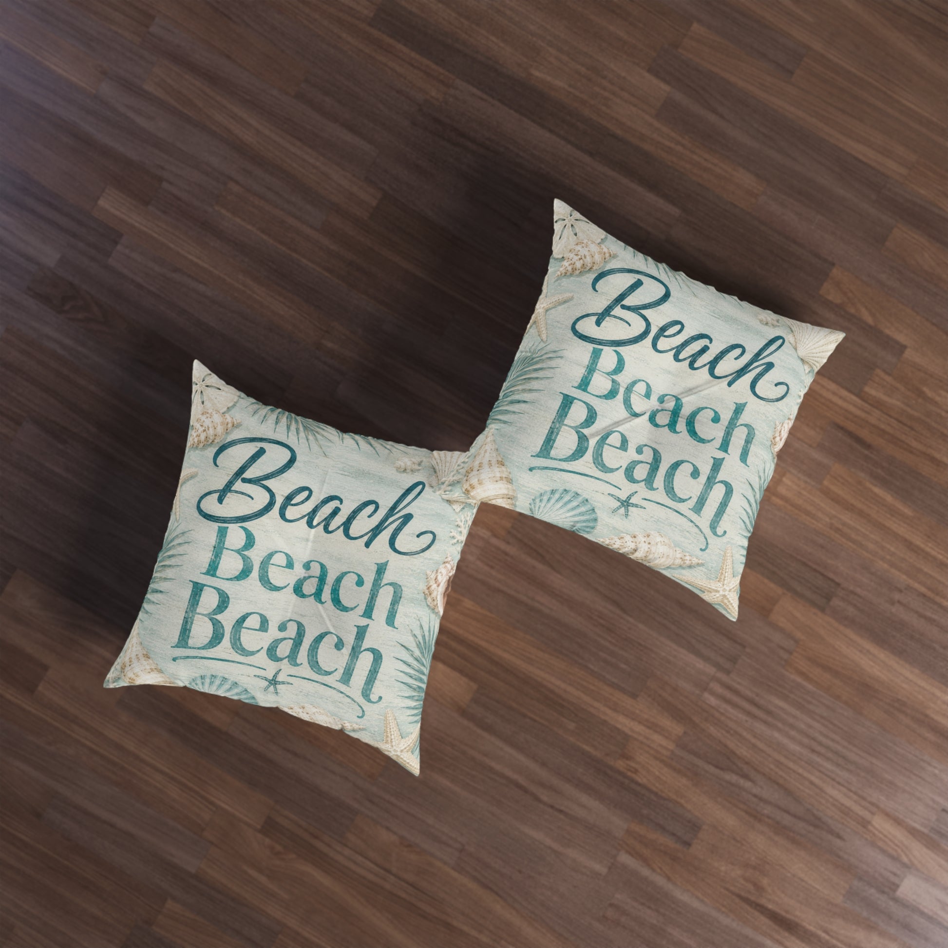 Square floor pillow with teal “Beach Beach” print and seashell accents, pair on wood floor