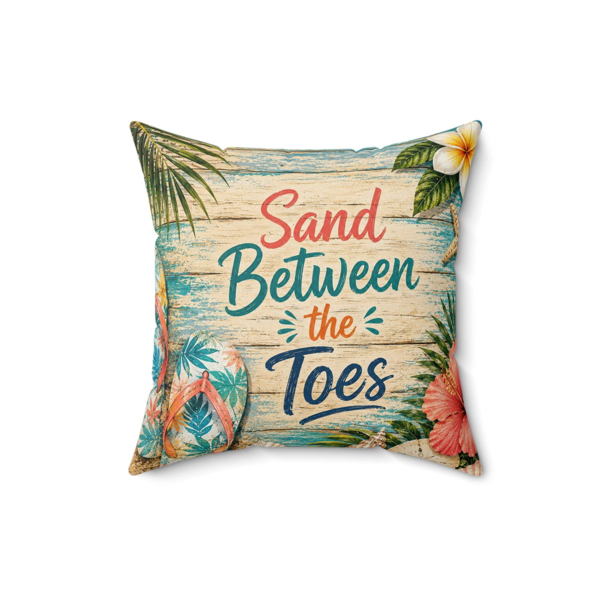 A square decorative throw pillow featuring a tropical beach design with the text 'Sand Between the Toes' in coral, teal, and navy lettering. The design includes palm leaves, a white hibiscus flower, pink flowers, and flip-flops on a weathered wood plank background, set against a plain white studio backdrop.