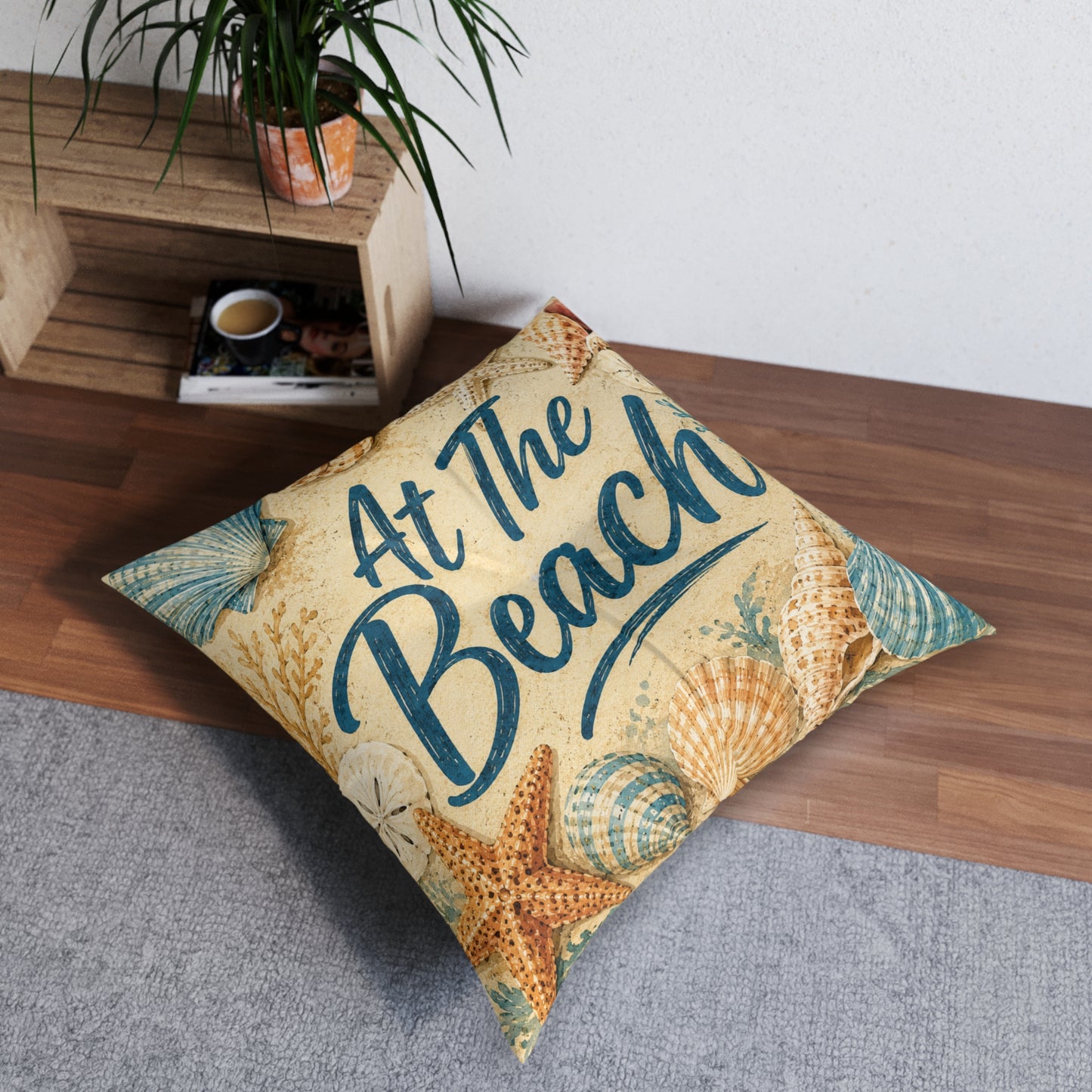Square tufted floor pillow, beige seashell print with teal 'At The Beach' lettering