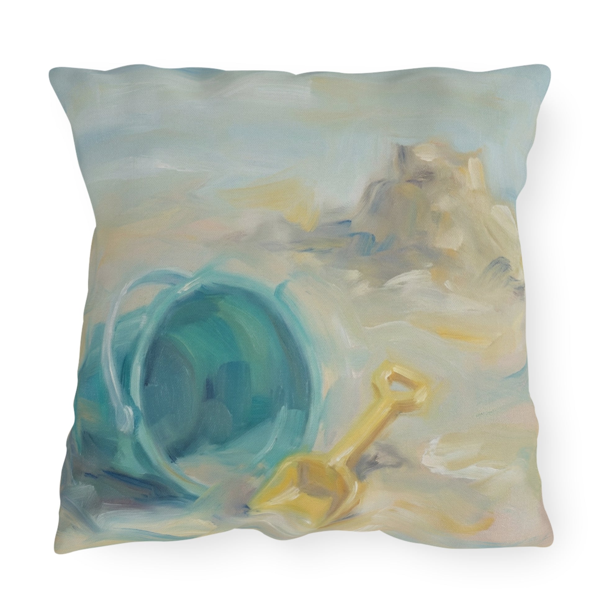 Decorative pillow with a beach-themed design featuring a sandcastle, bucket, and shovel.