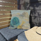 Decorative pillow with a blue and yellow design on a cushioned bench.