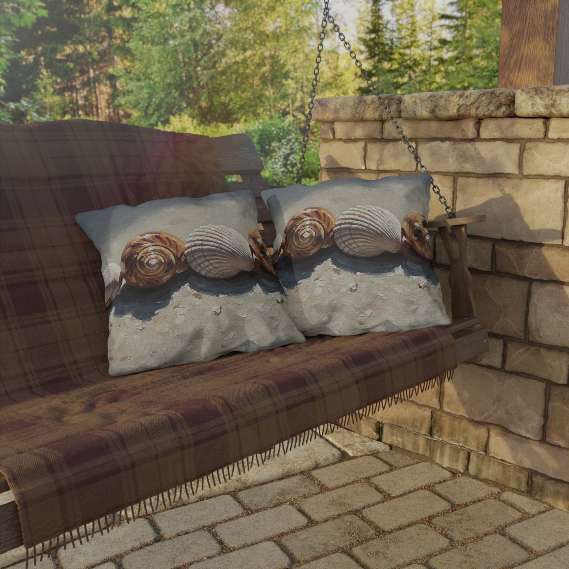 Decorative pillows with shell pattern on a wooden swing against a stone wall and greenery background