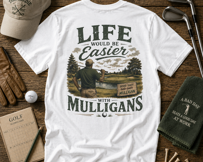 White t-shirt with golf-themed graphic and text on a wooden surface with golf accessories.