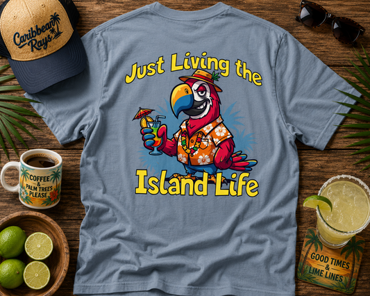 T-shirt with parrot graphic and 'Just Living the Island Life' text on a wooden surface with coffee, limes, and sunglasses.