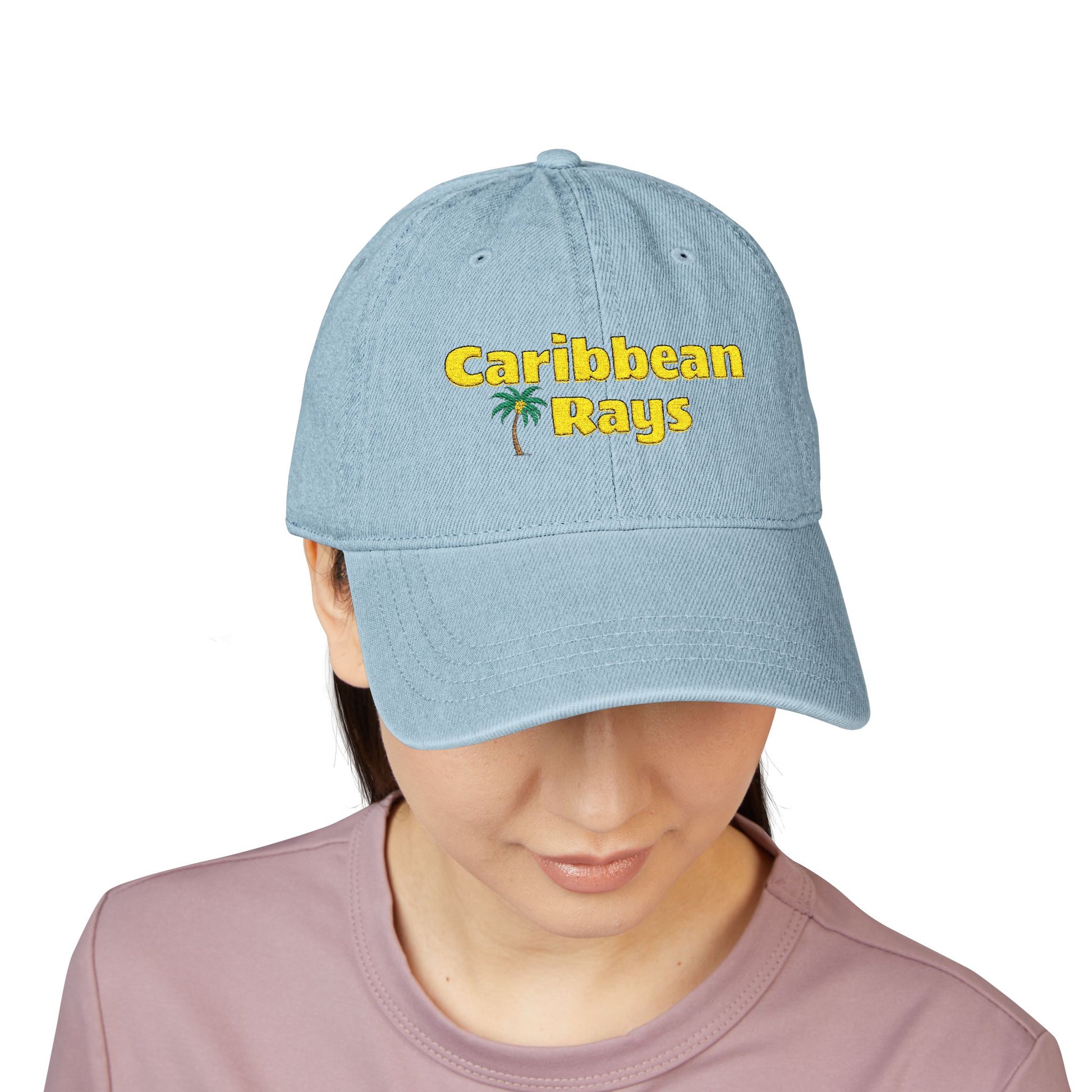 Light blue cap with 'Caribbean Rays' text worn by a person on a white background