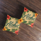 Square tufted floor pillows with Aloha lettering, hibiscus blooms, and palm leaf print on tan