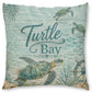 Square decorative throw pillow featuring a sea turtle underwater scene with the words 'Turtle Bay' in teal script, on a light aqua wood-plank style background.