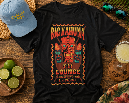 Black t-shirt with 'Big Kahuna Tiki Lounge' design on a wooden surface with a hat, limes, and a drink.
