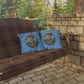 Two blue pillows with a cartoon character on a wooden swing set against a stone wall and greenery.