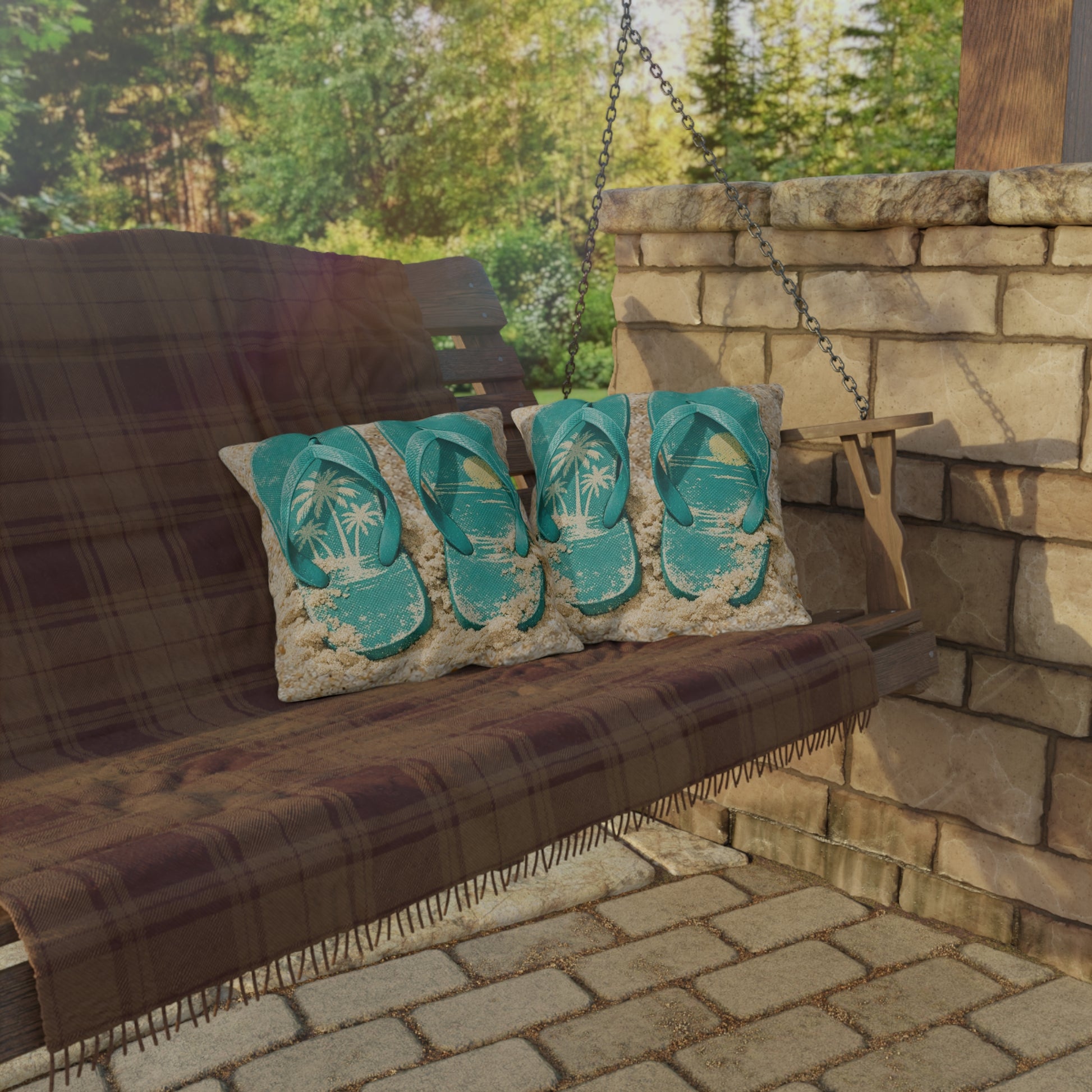 Porch swing with flip-flop patterned pillows against a stone wall and greenery.