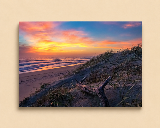 Beach scene with sunset, waves, and sand dunes on a beige background