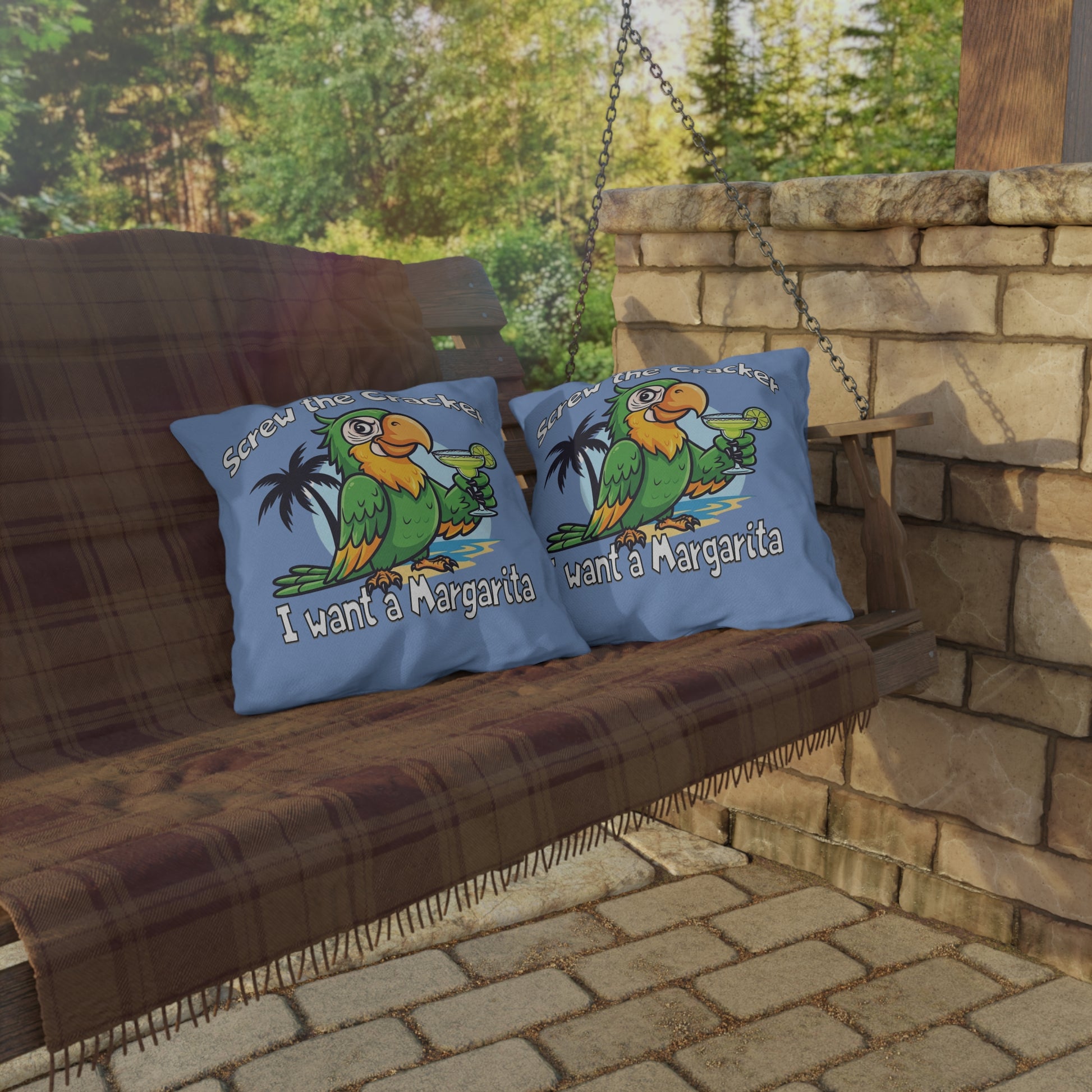 Two pillows with a parrot design and text on a wooden swing against a stone wall and greenery background.