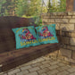 Two colorful pillows with a parrot design and 'Island Life' text on a wooden swing.