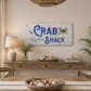 Nautical-themed decor with 'The Crab Shack' sign in a dining room.