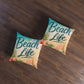 Square tufted floor pillow set, 'Beach Life' print in beige and teal.