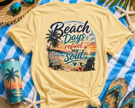 Yellow t-shirt with 'Beach Days refuel my Soul' design on a blue and white striped towel with beach accessories.