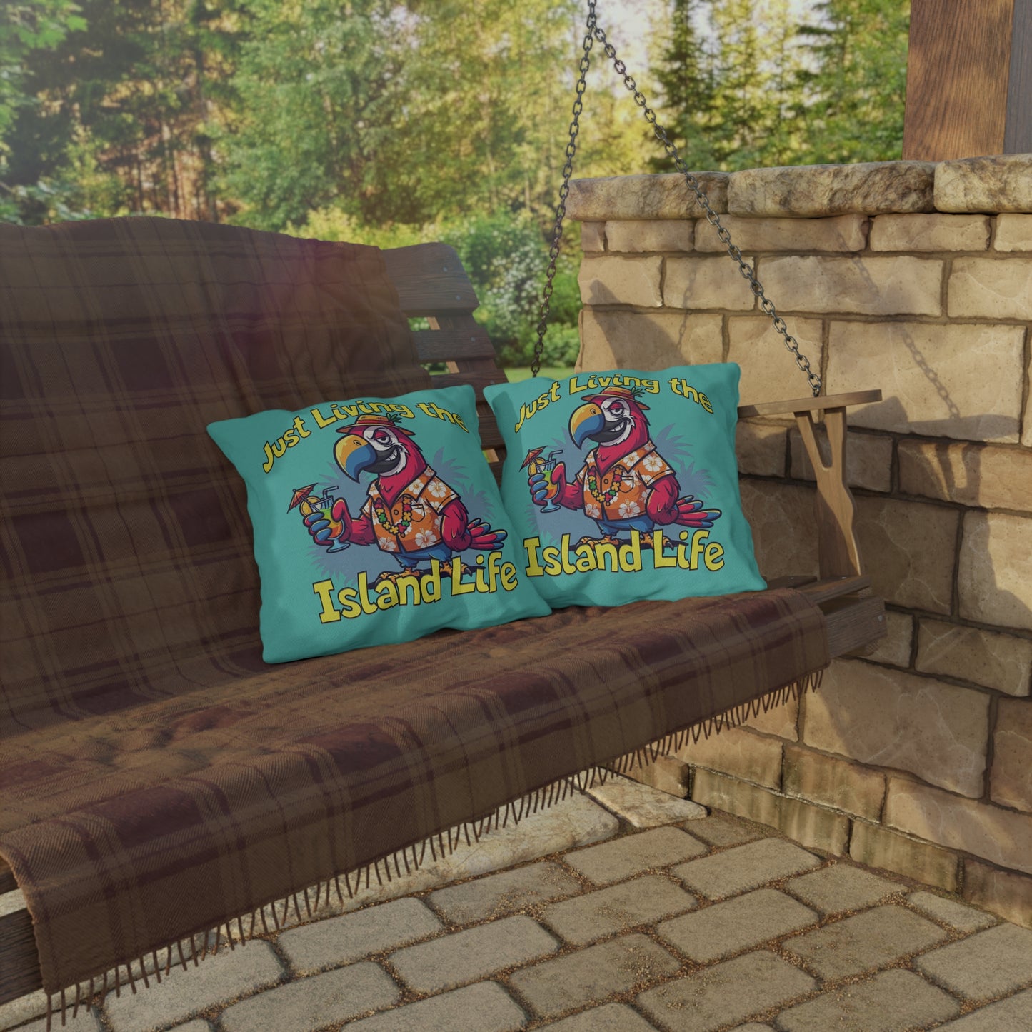 Two pillows with 'Island Life' design on a wooden swing against a stone wall and greenery background.