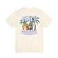 Beige t-shirt with 'Beach Paradise' graphic featuring a palm tree, lounge chair, and sunglasses on a white background by Caribbean Rays