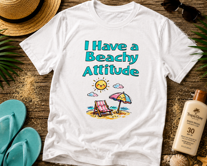 White t-shirt with 'I Have a Beachy Attitude' text and beach graphics on a wooden surface with summer items.