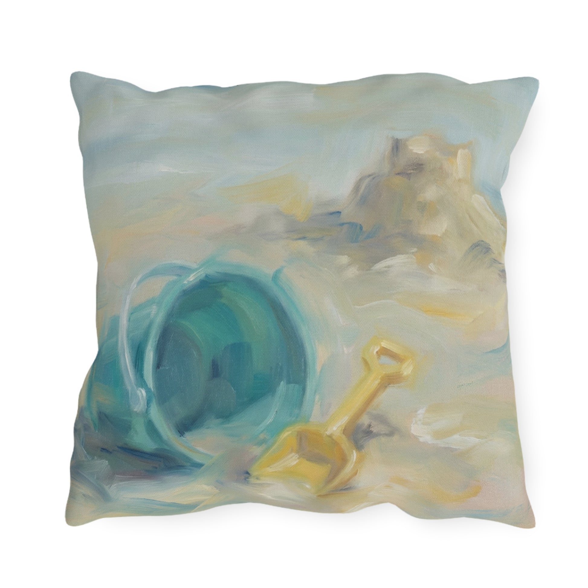 Decorative pillow with a beach scene featuring a blue sand bucket and yellow shovel.
