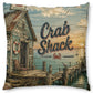 A square decorative throw pillow featuring a vintage-style printed illustration of a crab shack by the water, with the words “Crab Shack” and a small crab graphic on the front.
