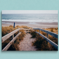 Wooden pathway leading to a beach with grass and ocean view on a light blue background