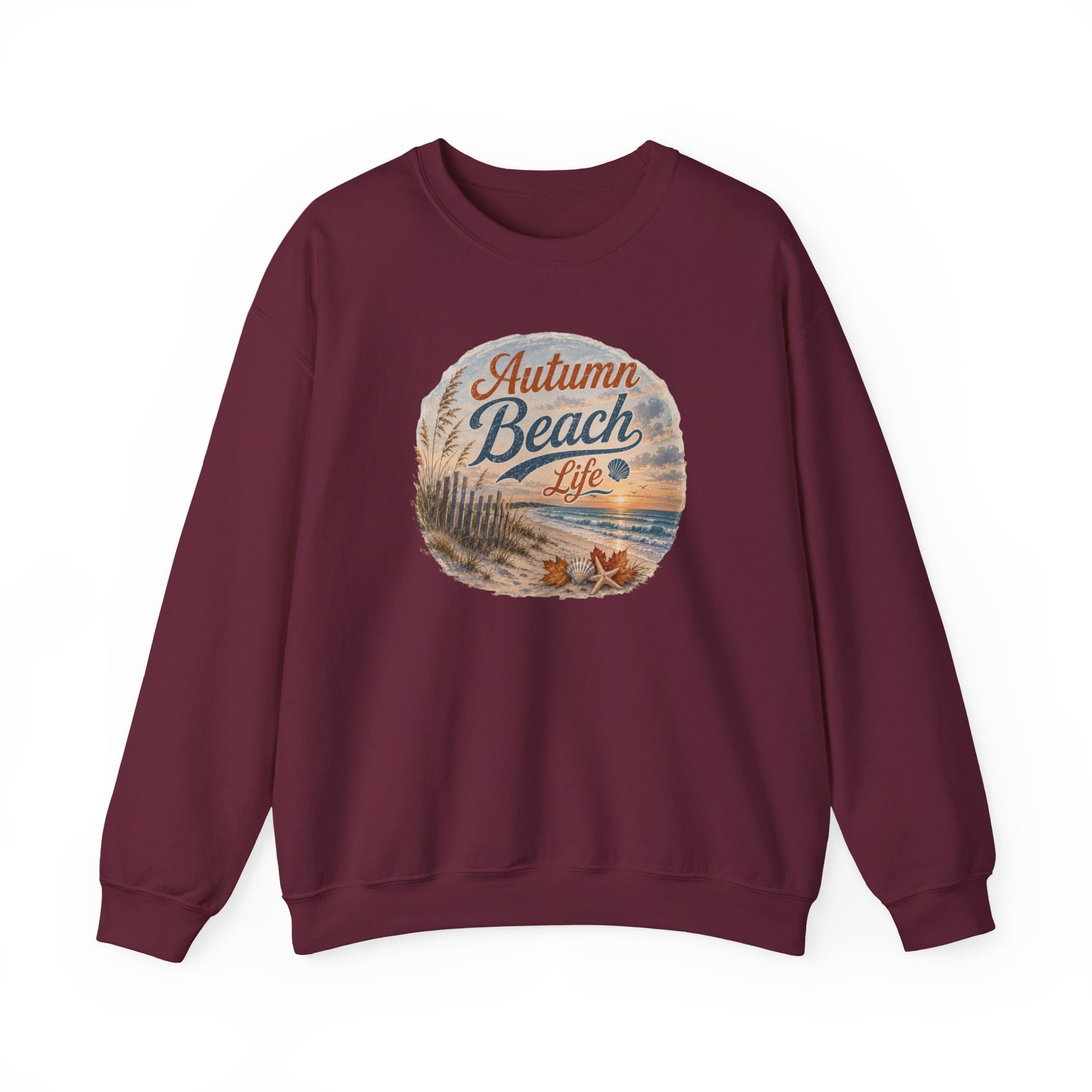 A maroon crewneck sweatshirt with a circular graphic on the chest that reads 'Autumn Beach Life' in stylized lettering over a beach scene illustration, shown against a plain white background.