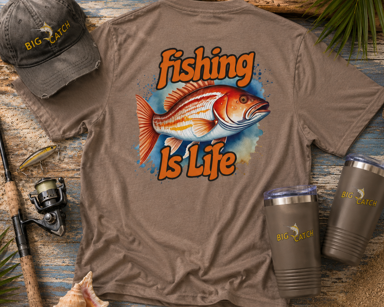 Brown t-shirt with 'Fishing is Life' design, cap, and tumblers on a wooden surface.