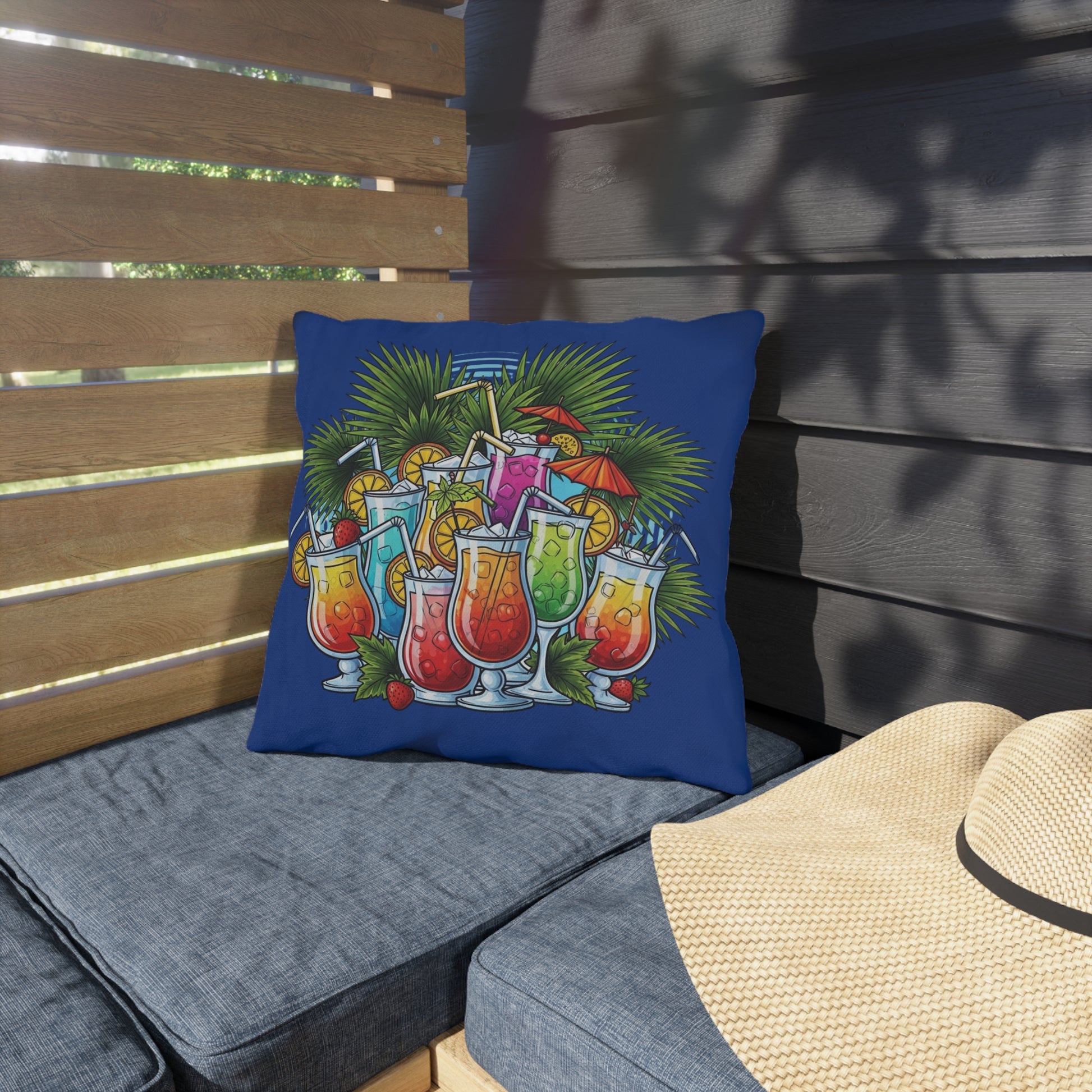 Decorative pillow with tropical drink design on a gray cushioned chair outdoors.