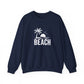 A navy blue crewneck sweatshirt with a white graphic on the chest depicting a palm tree, a rising sun, birds, and the word 'BEACH'.