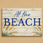 Decorative sign with 'At the Beach' text on a wooden background