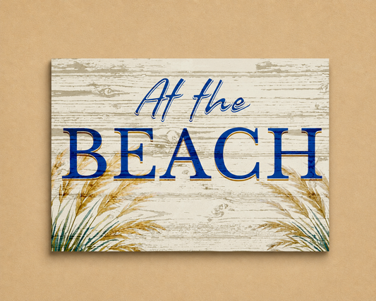 Decorative sign with 'At the Beach' text on a wooden background