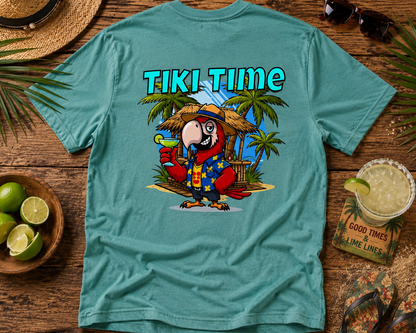 Teal t-shirt with a parrot graphic and 'Tiki Time' text on a wooden surface with tropical items.
