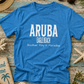 Blue t-shirt with 'ARUBA EAGLE BEACH Another Day in Paradise' text on a wooden surface with beach-themed items.